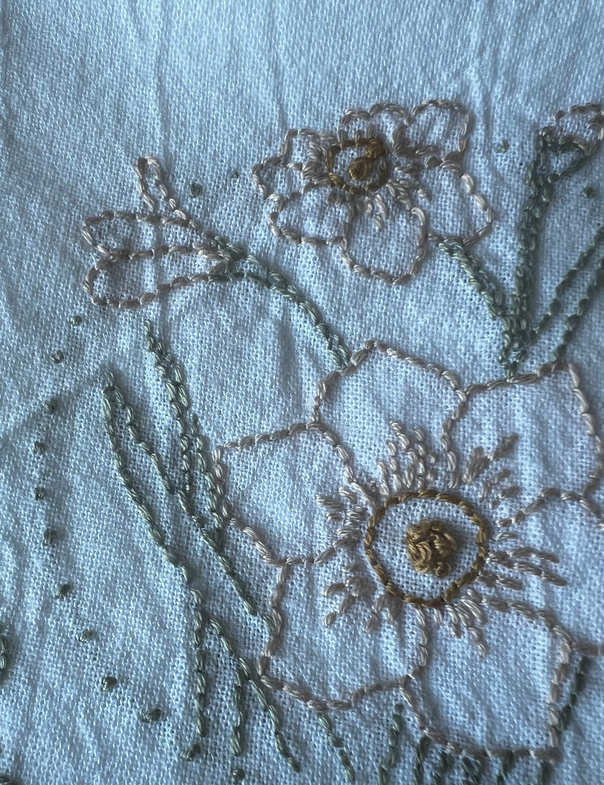 Hand-embroidered narcissus blooms, gold centers, green stems, dotted border, close-up