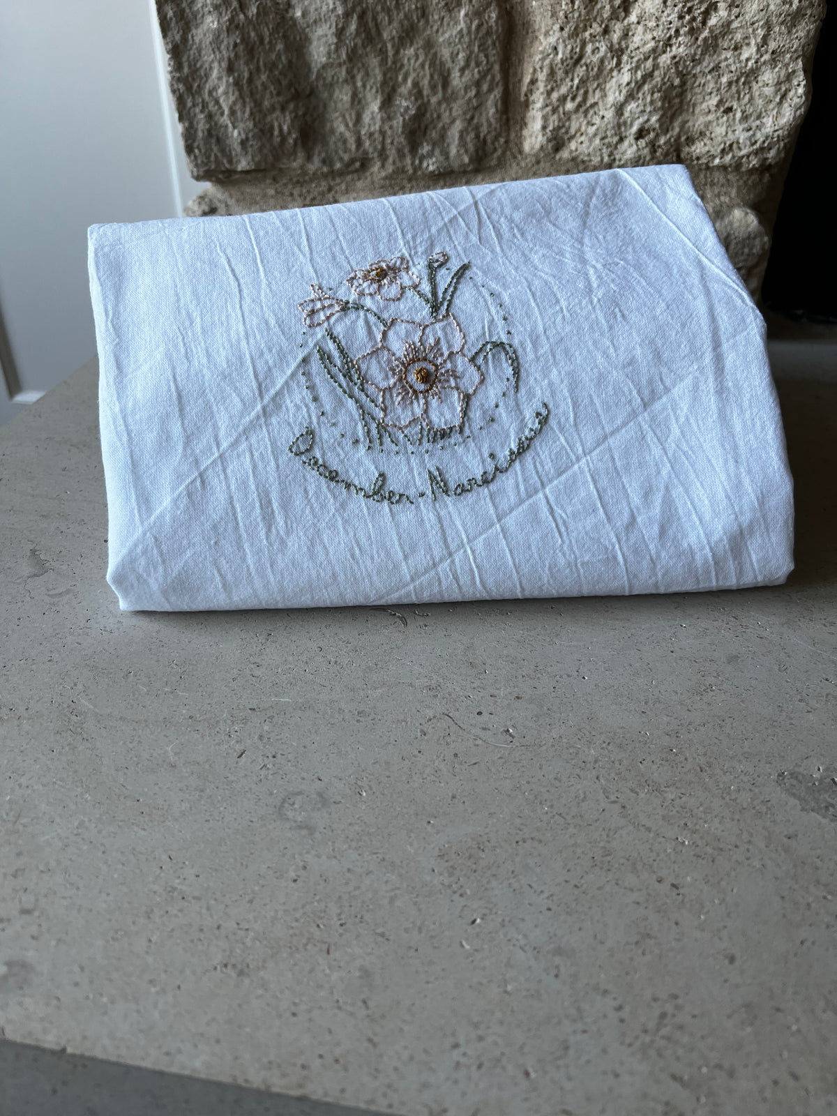 Hand-embroidered cotton tea towel, narcissus in dotted circle, December Narcissus script