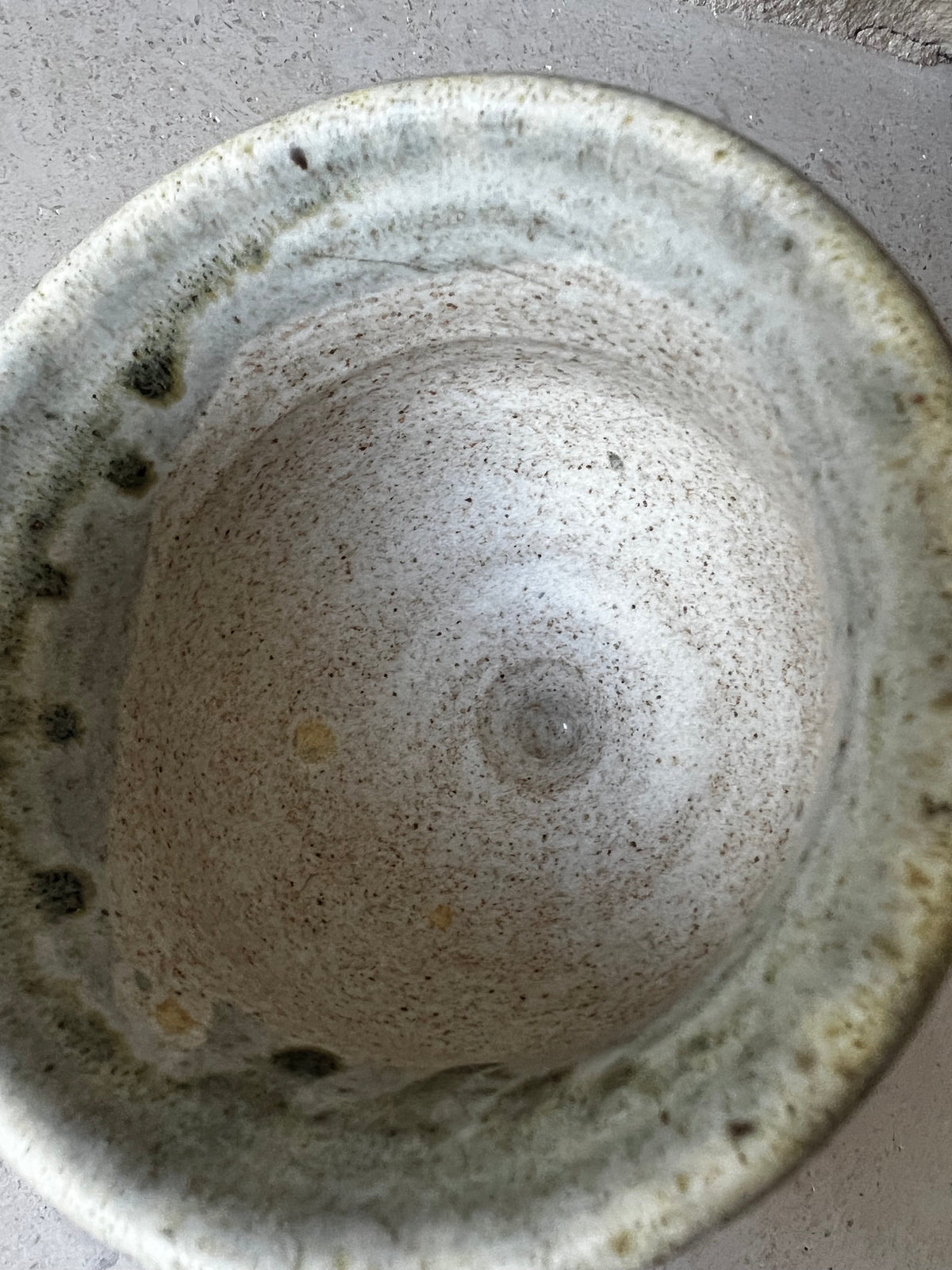 Interior of stoneware goblet, speckled oatmeal glaze, throwing rings, green-gray rim