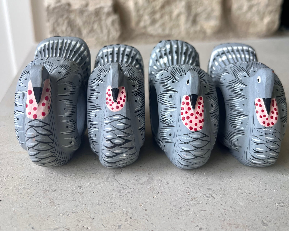 Front view of four vintage wooden turkey napkin rings showing their painted faces and colorful feathers. 