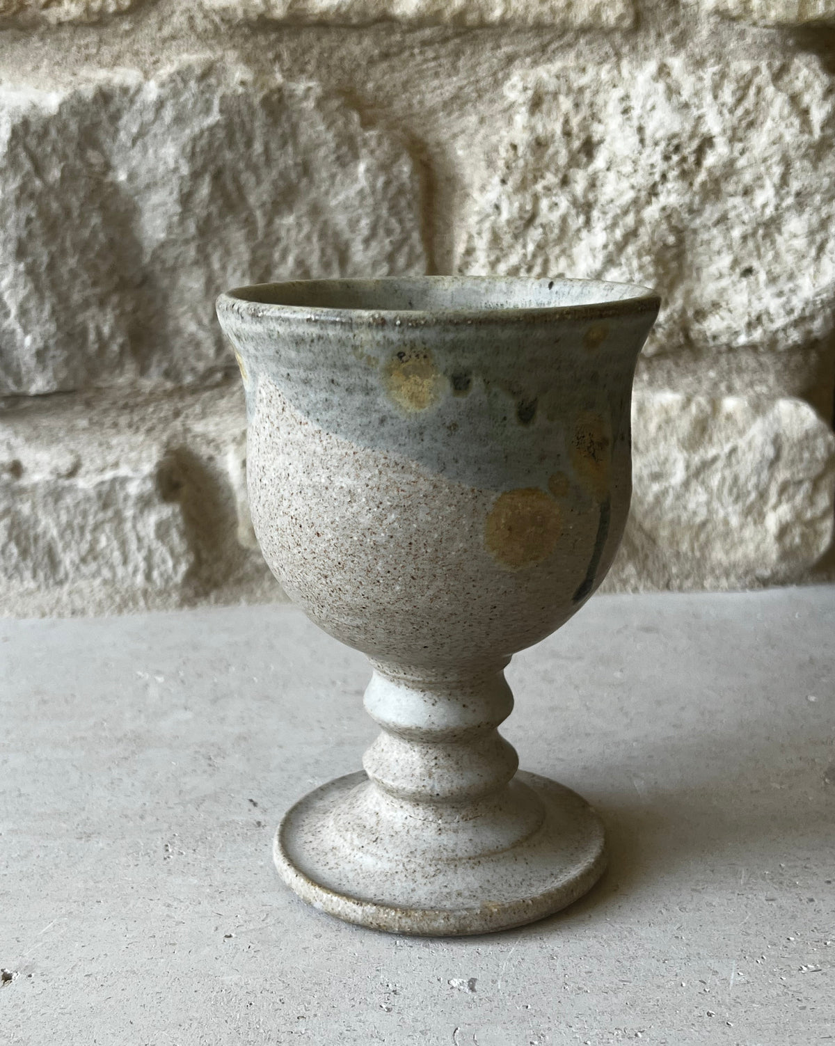 RT-stamped wheel-thrown stoneware goblet, speckled oatmeal glaze, blue-gray rim with drips