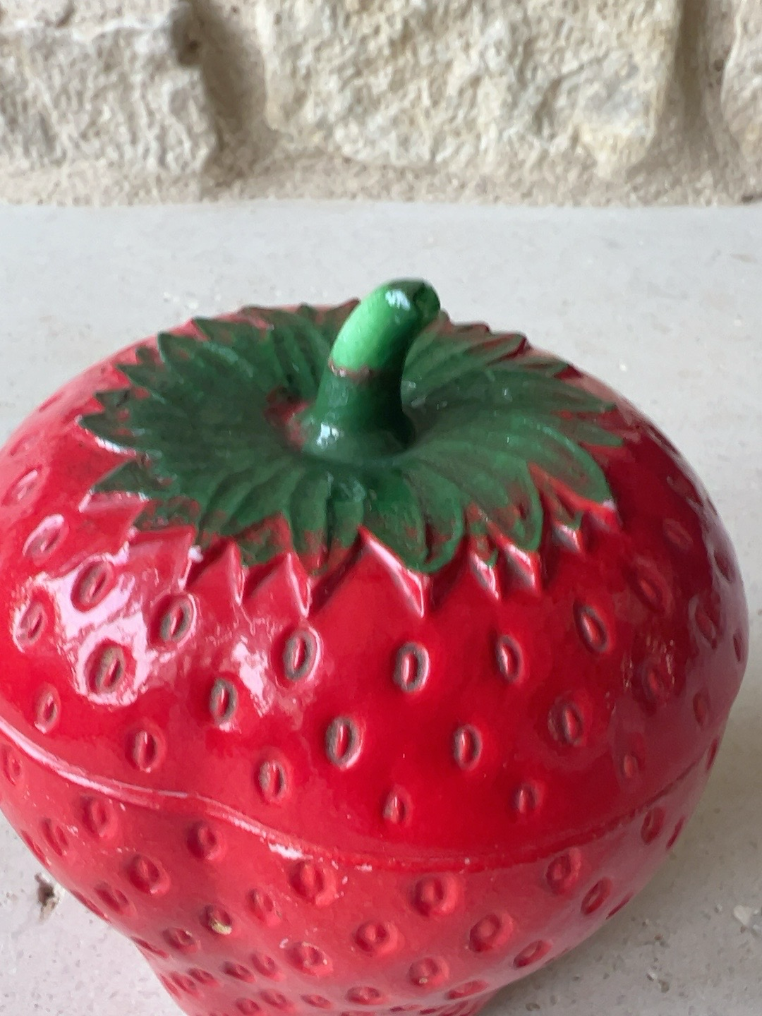 Close up of strawberry jar showing other side of paint wear on surface details. 