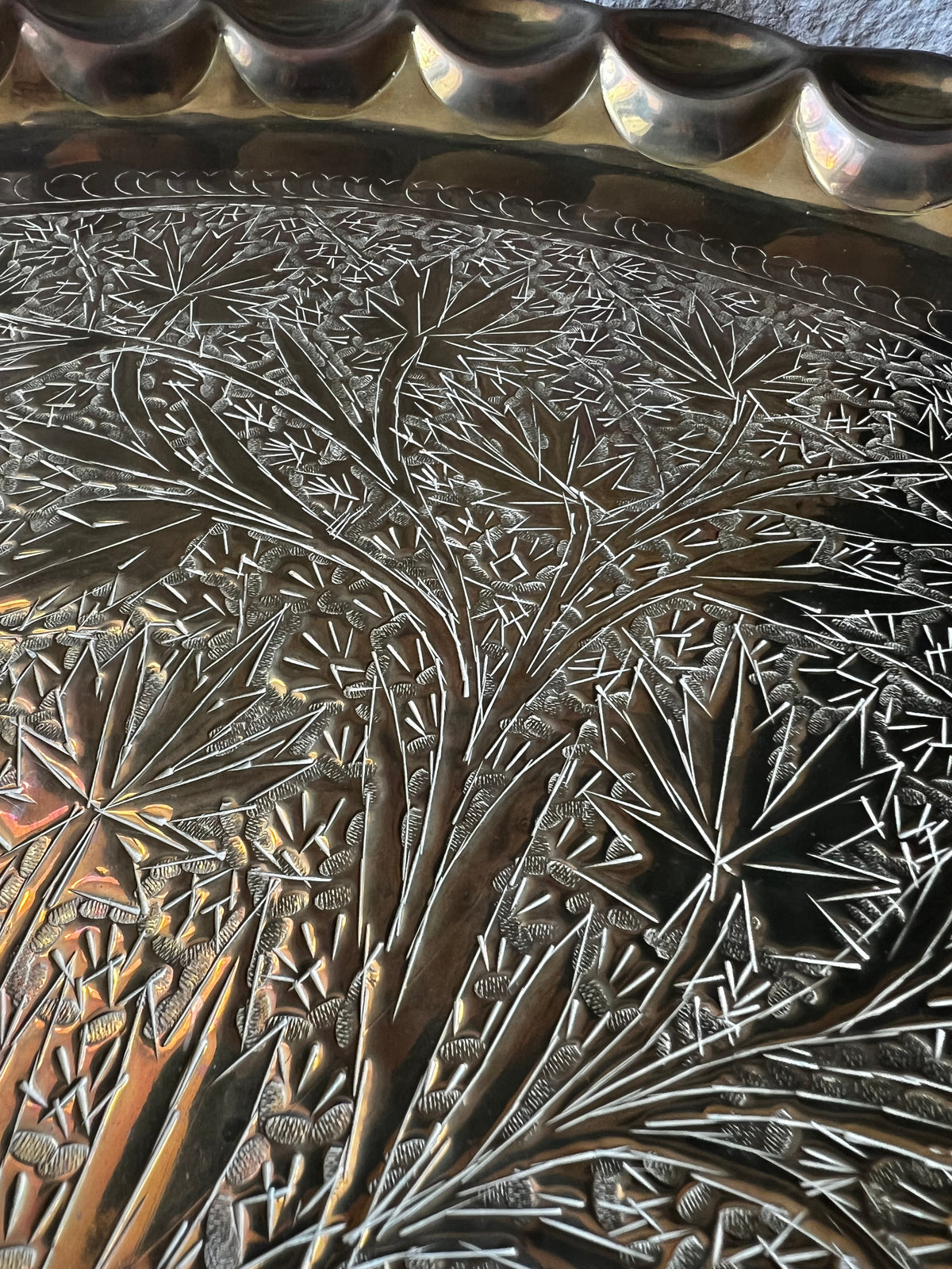 Detail of hand-chased foliate engraving on brass tray.