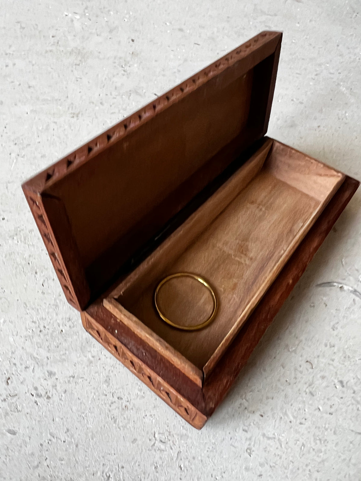     Open vintage carved wooden box with gold ring for scale