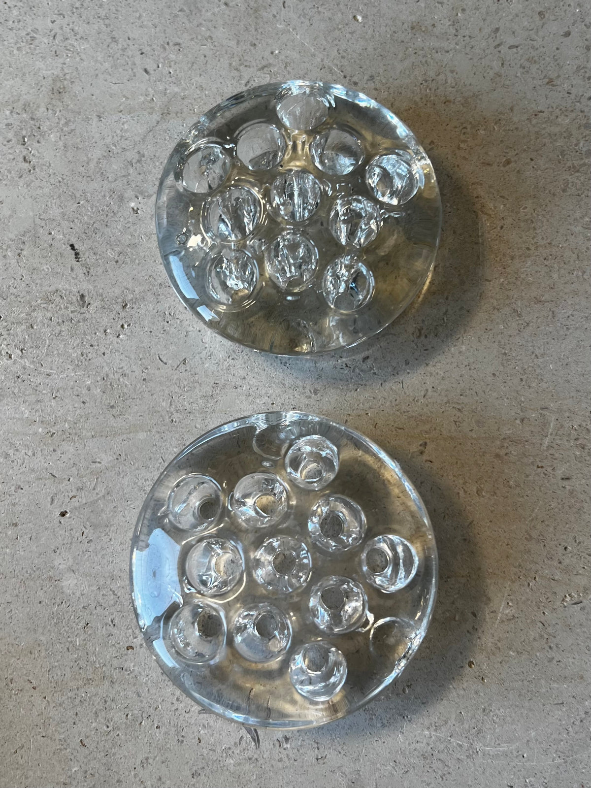Two small round clear pressed glass flower frogs, overhead view of stem holes