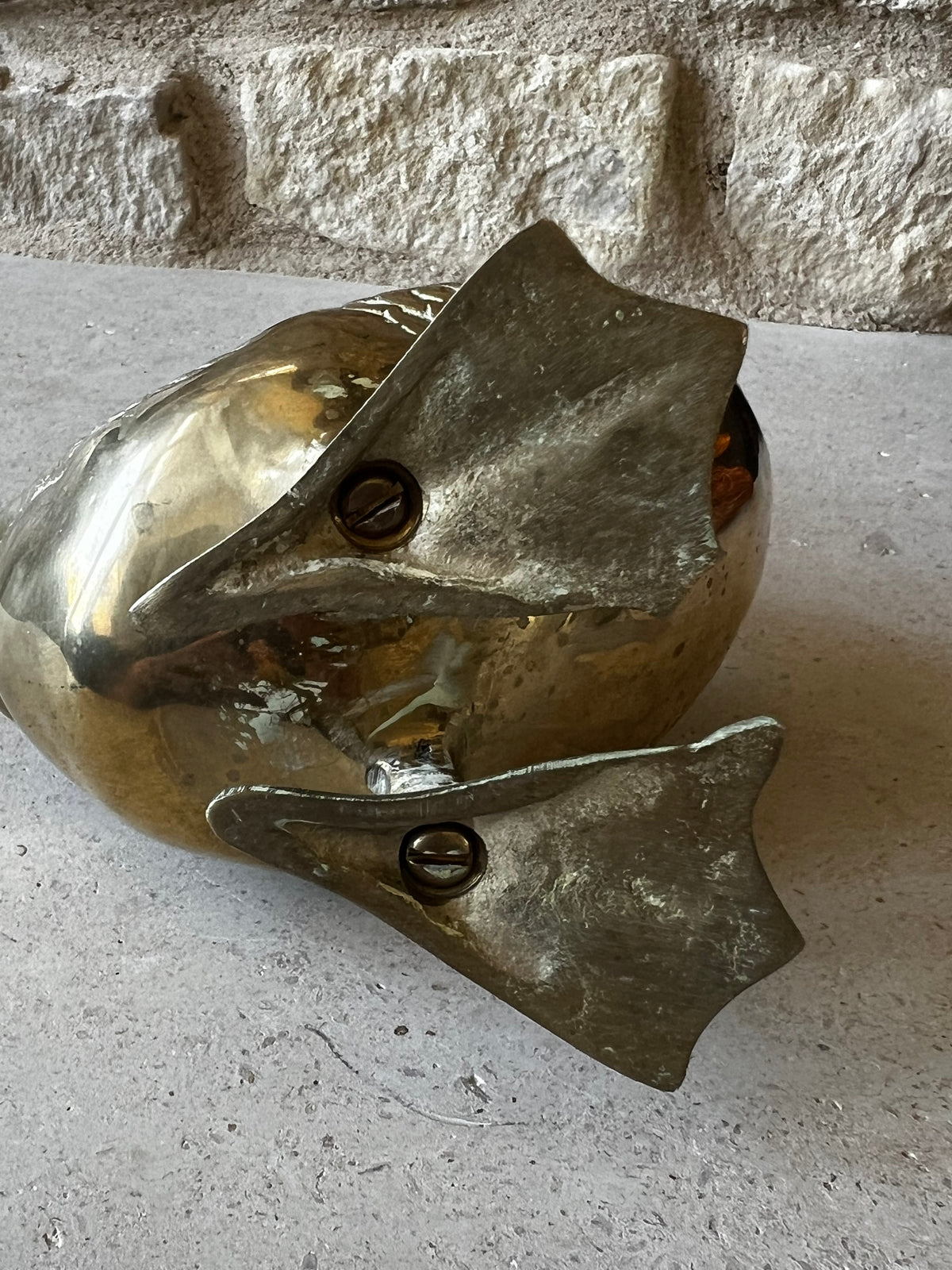Underside of vintage brass goose showing attached webbed feet and slotted screws