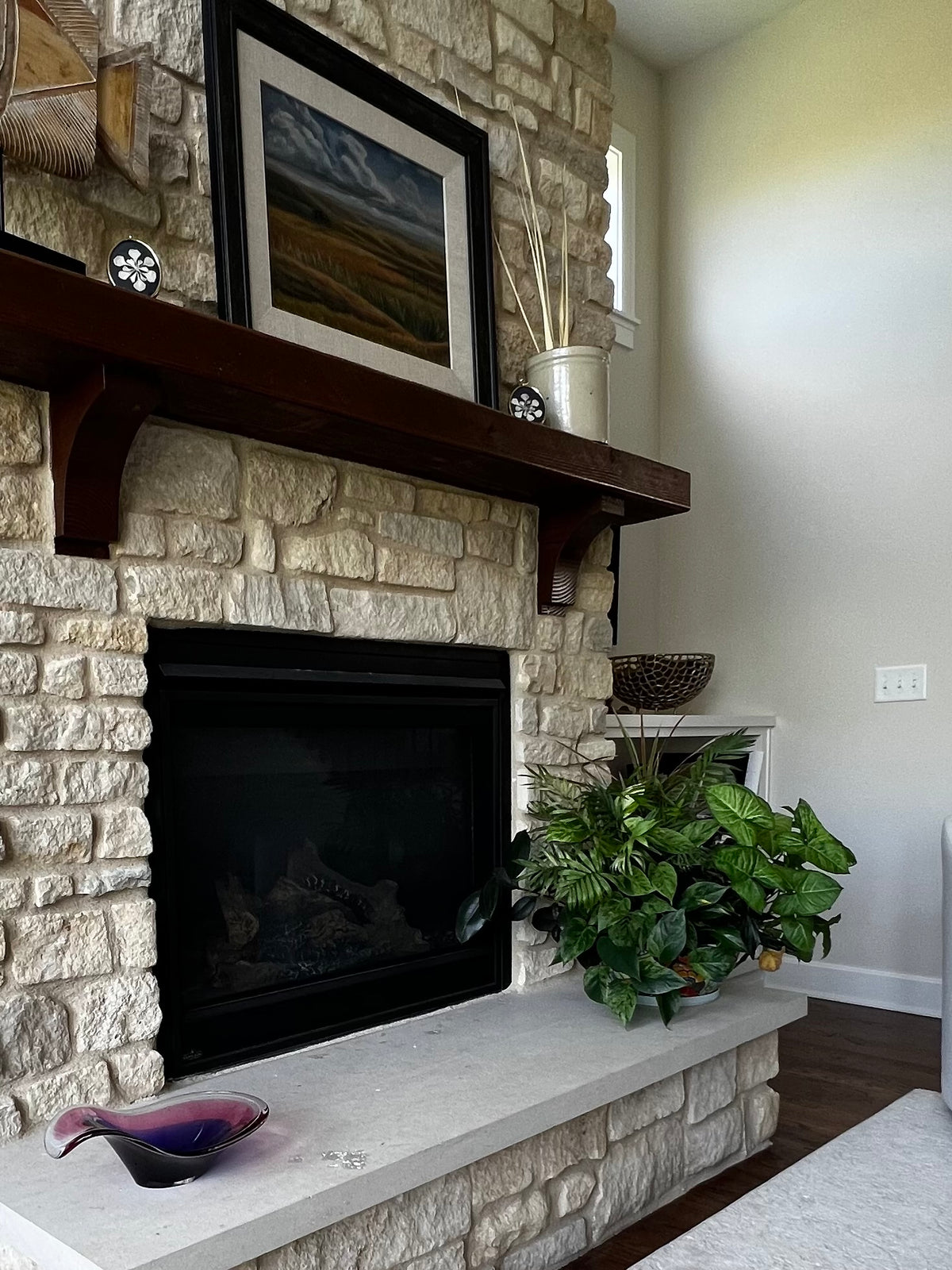 Vintage pink and blue art glass bowl displayed beside a stone fireplace. 