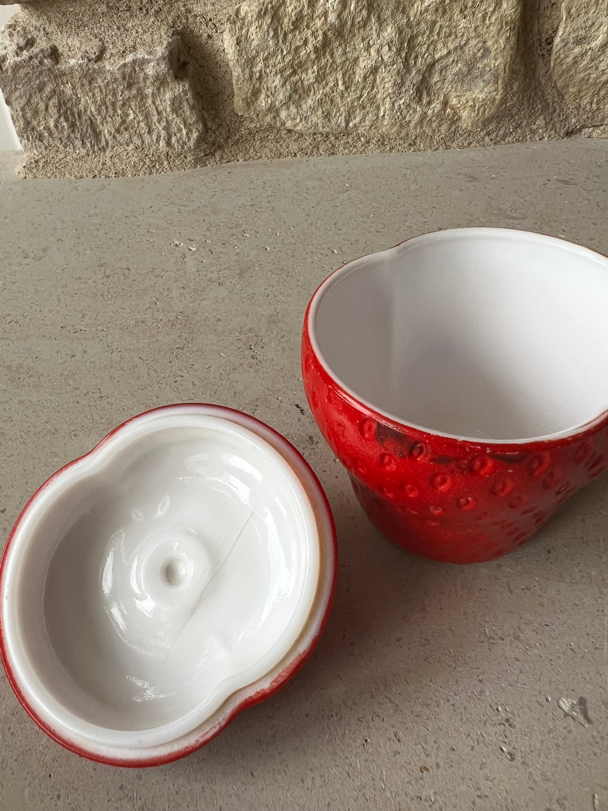 Open strawberry milk glass jar showing white interior and removable green topped lid. 