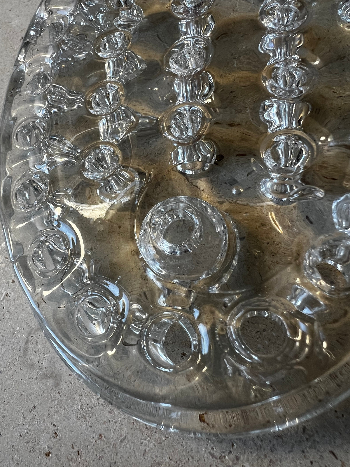 Close-up of raised candle socket on oval pressed glass flower frog, molded stem holes