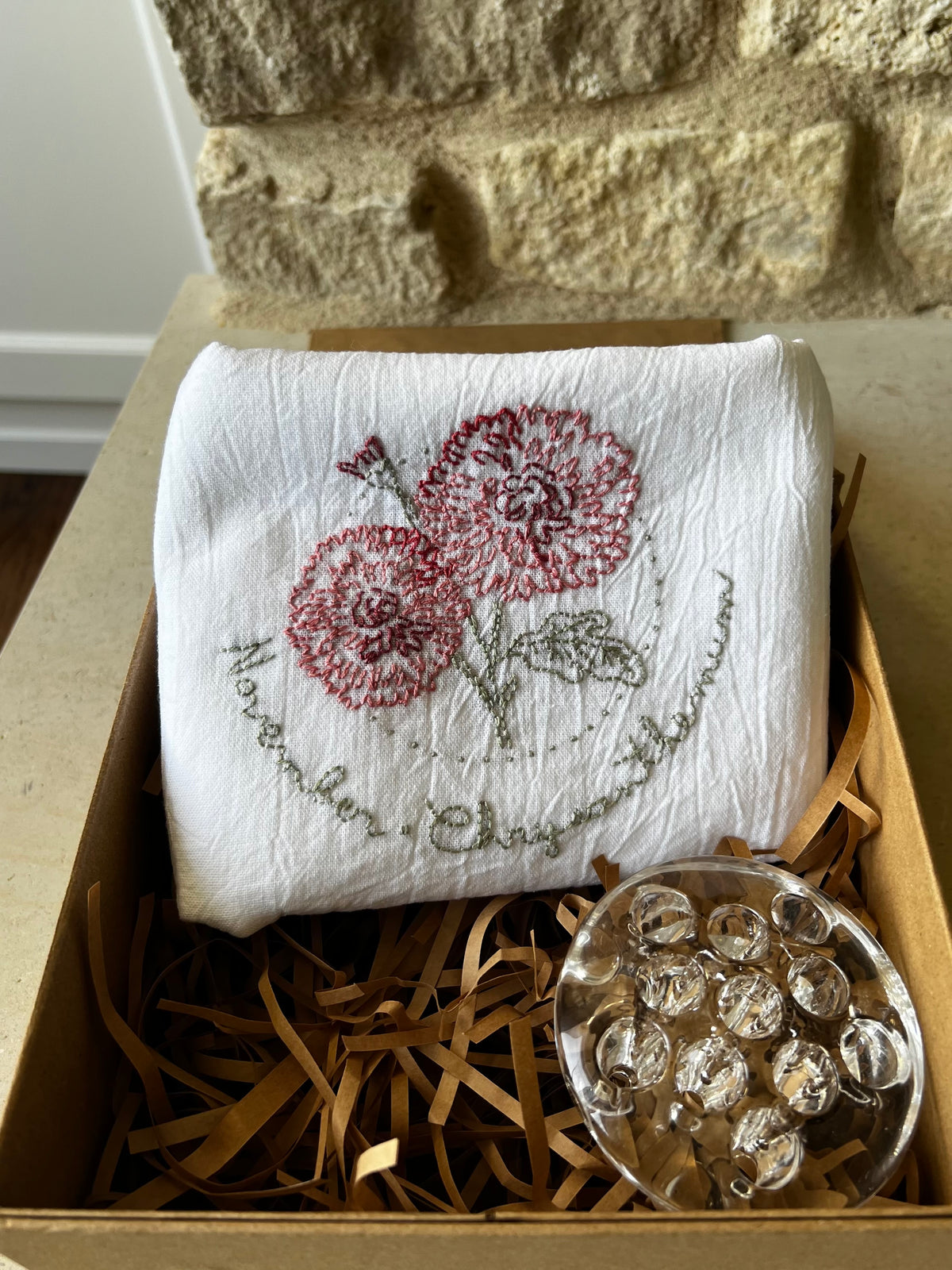 Hand-embroidered chrysanthemum tea towel with clear glass flower frog in kraft gift box