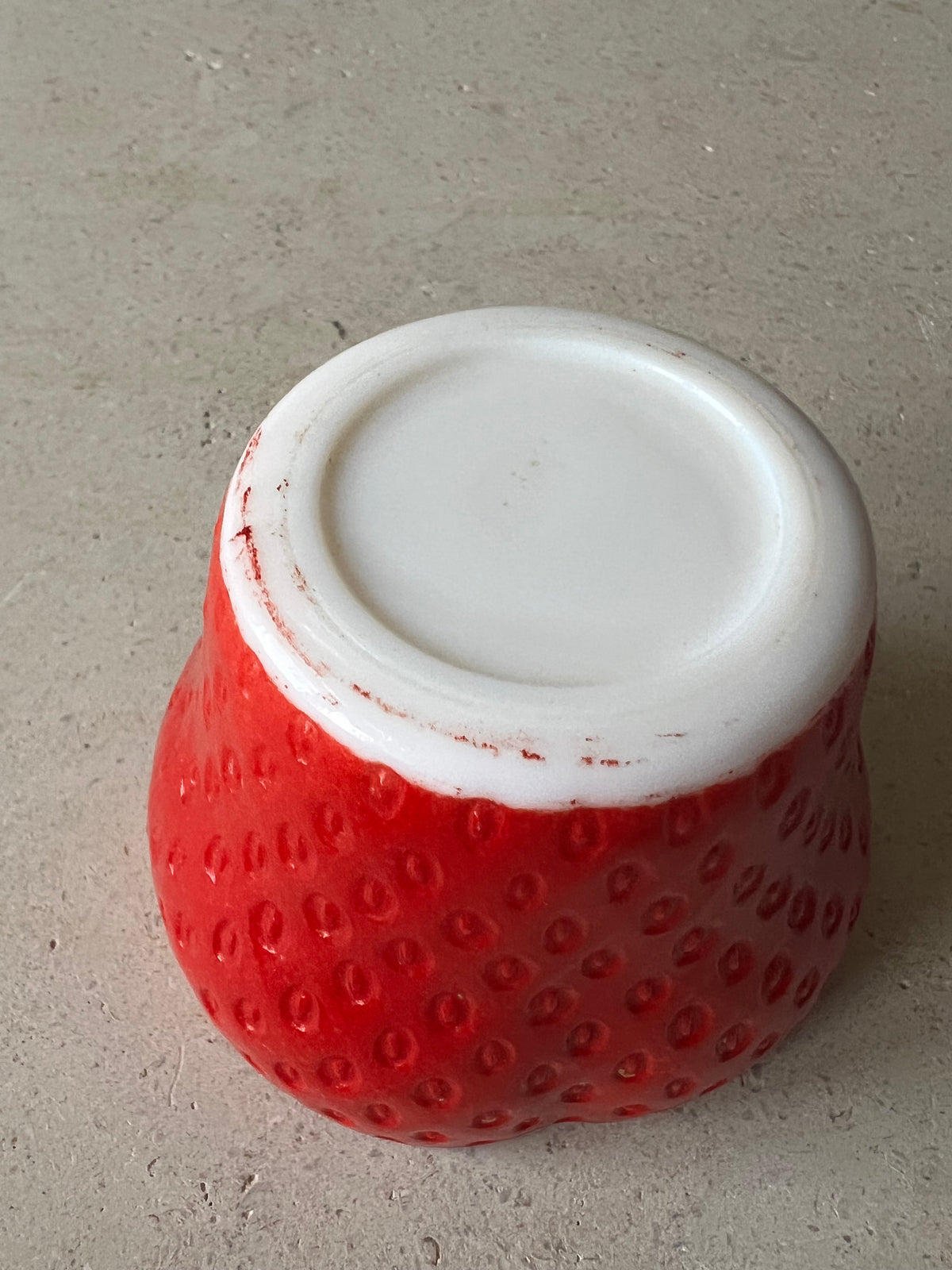 Underside of vintage strawberry milk glass jar showing white glass base. 