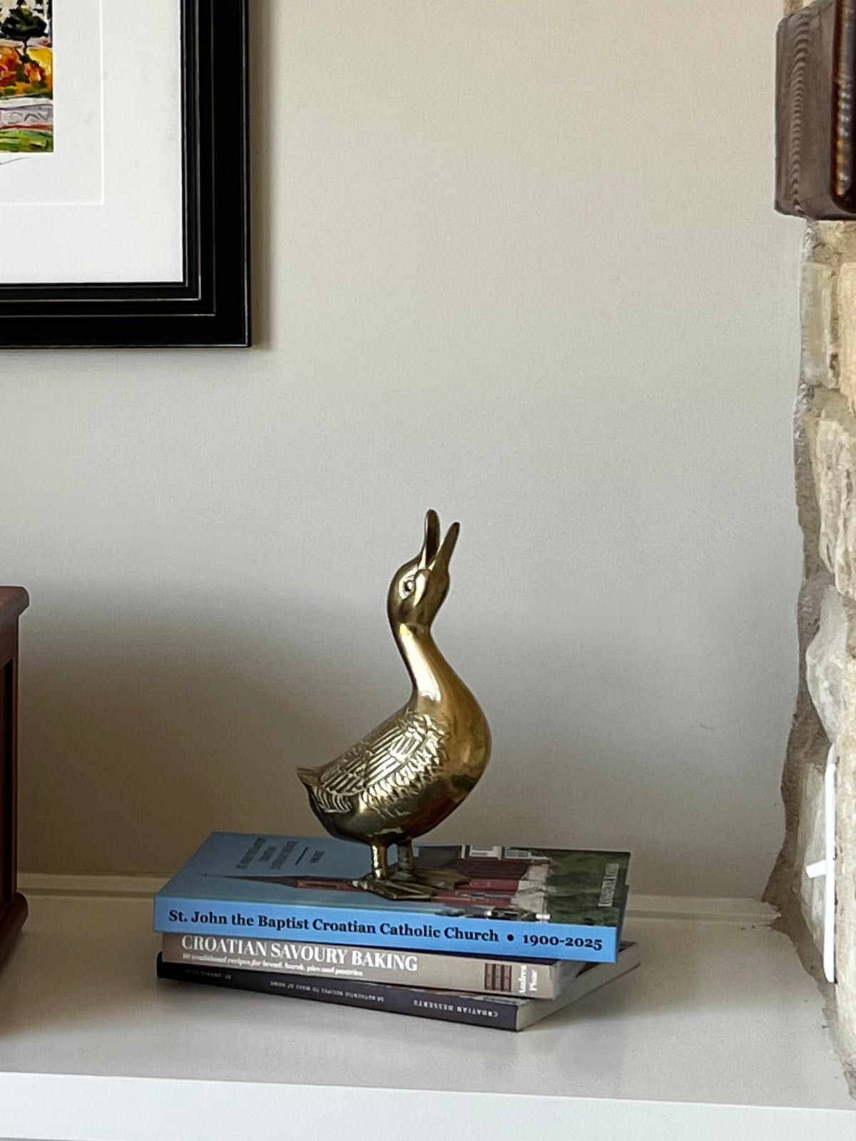 Vintage brass goose sculpture displayed on books in a home interior