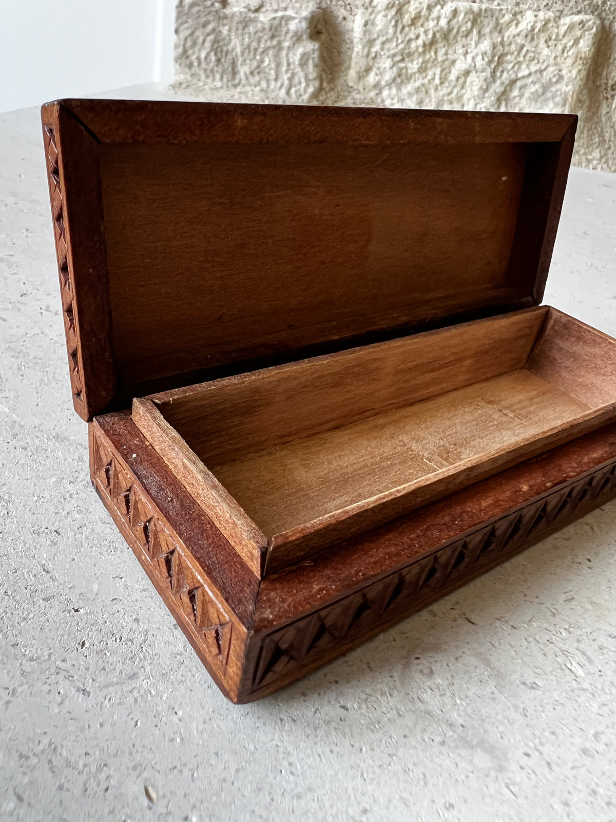    Open vintage hand-carved wooden box showing plain wood interior