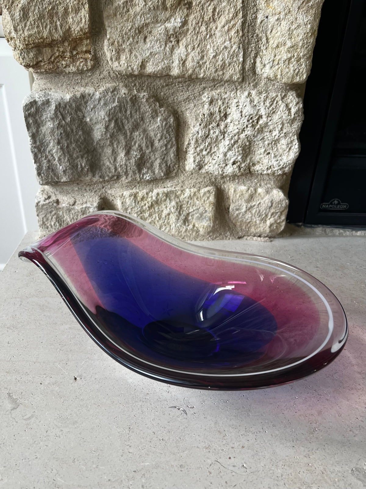 Front view of Flysfors glass bowl showing its curved pink and blue glass form. 