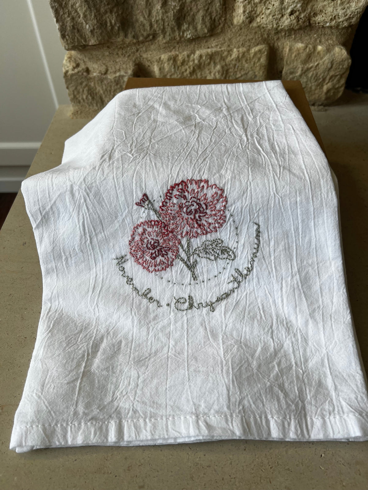 Hand-embroidered cotton tea towel, red chrysanthemum in dotted circle, November script