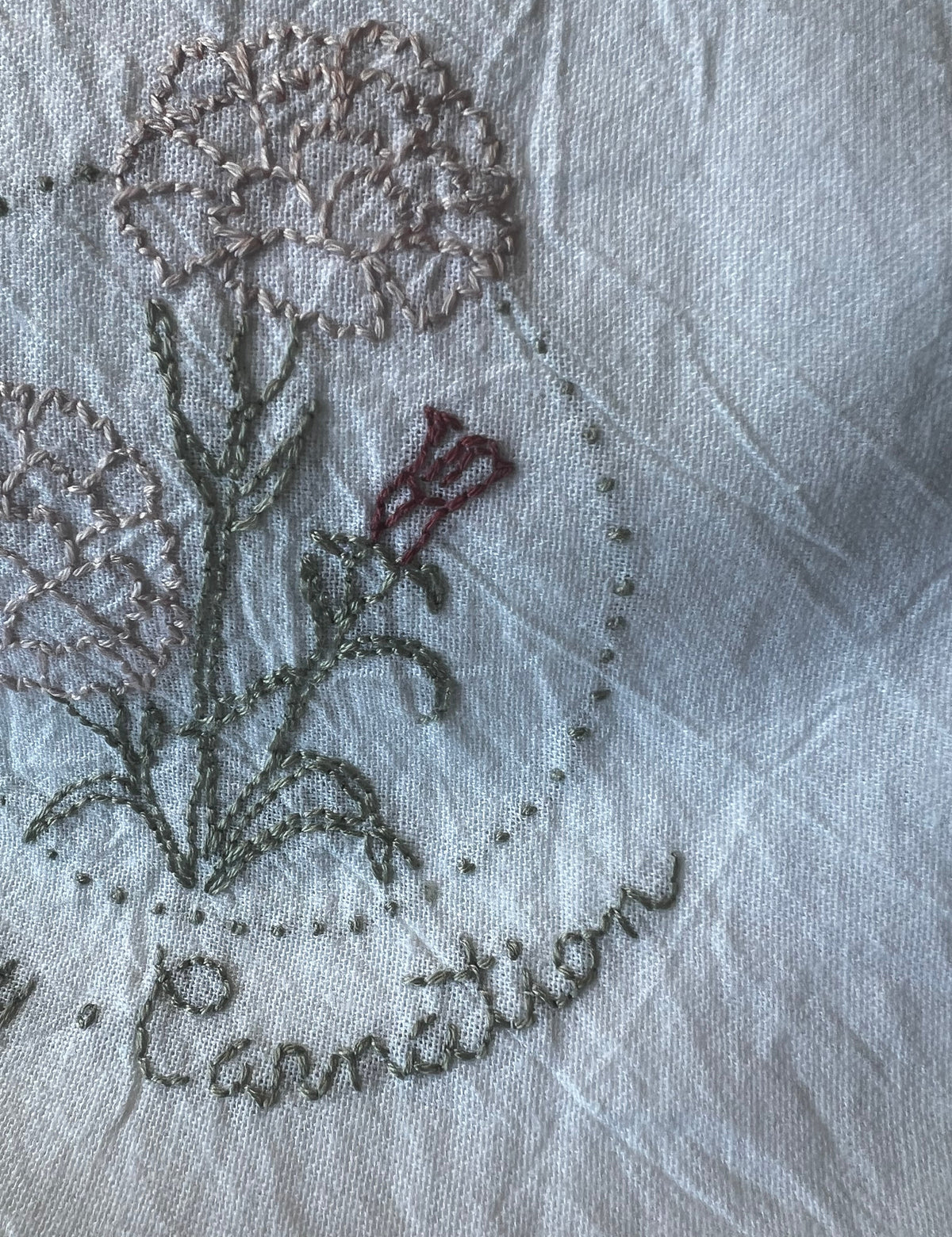 Hand-embroidered cotton tea towel, pink carnation in dotted circle, January Carnation script