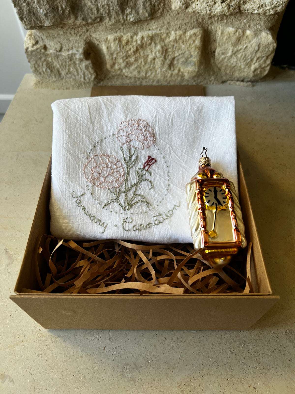 Hand-embroidered carnation tea towel with W. Germany glass clock ornament in kraft gift box