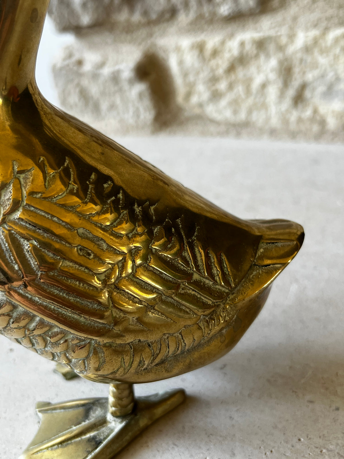 Close view of detailed feather work and aged patina on vintage brass goose
