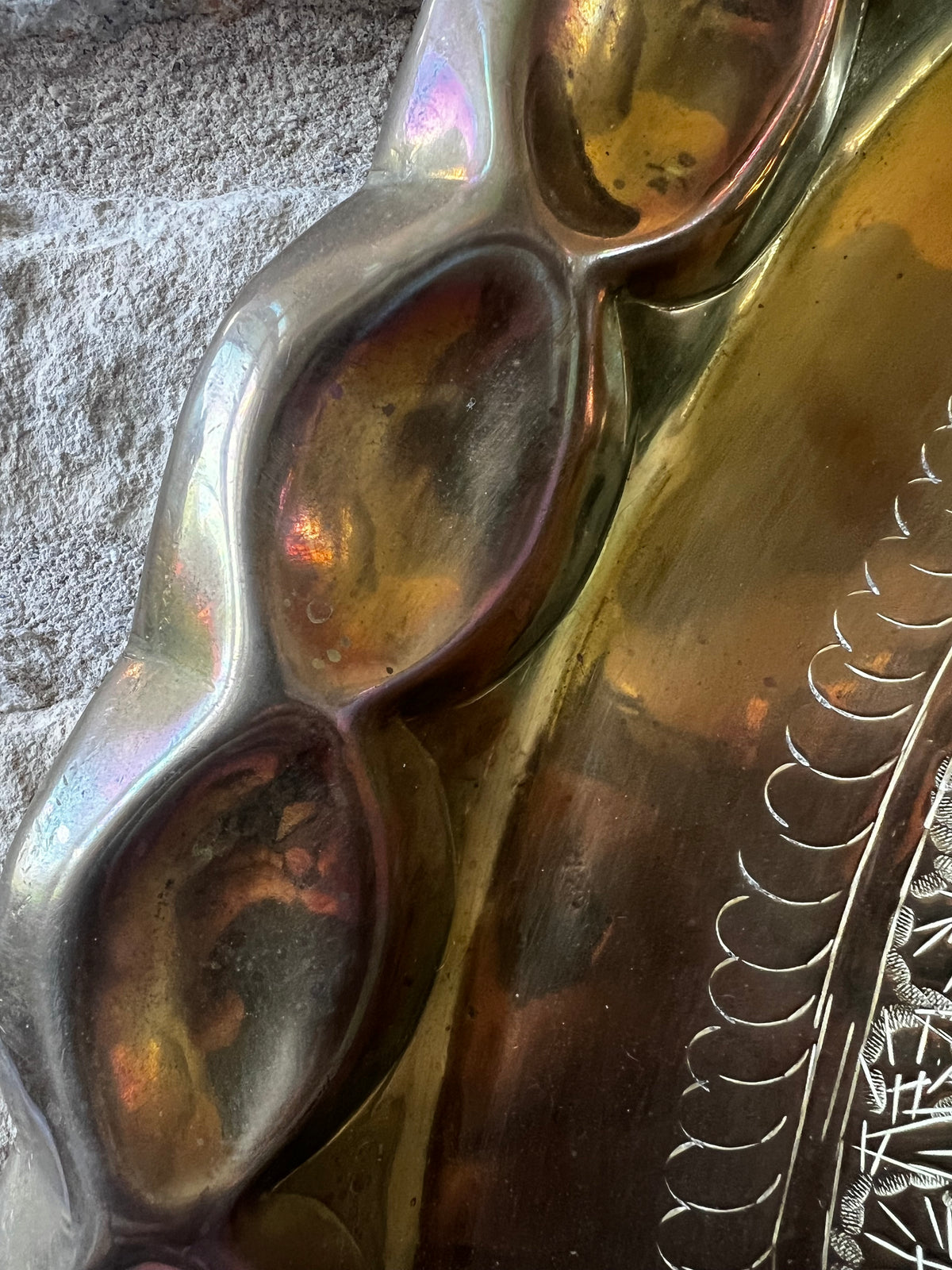 Detail of scalloped rim and natural iridescent patina on brass tray.